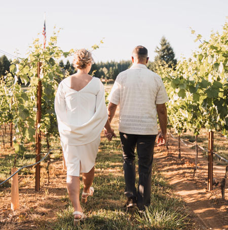 Couple walking hand in hand through the vineyard