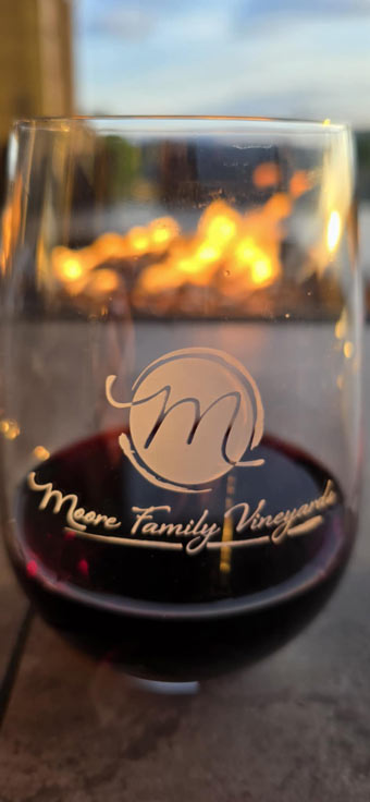Wine glass with Moore Family Vineyards logo by the fire pit