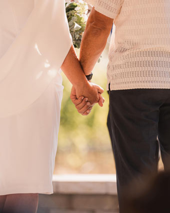 Close-up of couple holding hands during wedding ceremony