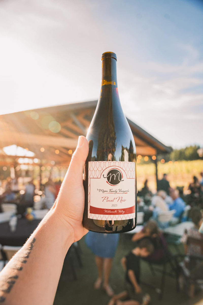 Moore Family Vineyards wine bottle held against vineyard backdrop